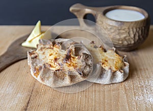 Finnish Traditional Pasties - Karelian Pies From Region Of Karelia. Table with a wooden mug kuksa full of milk