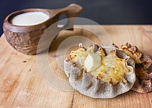 Finnish Traditional Pasties - Karelian Pies From Region Of Karelia. Table with a wooden mug kuksa full of milk