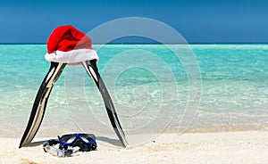 Fins and mask with Christmas hat on a tropical beach
