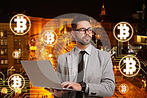 Fintech concept. Scheme with bitcoin symbols and businessman using laptop on cityscape