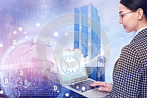 Fintech. World globe with bitcoin symbols and businesswoman using laptop on cityscape background
