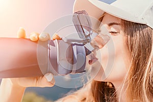 Fintess woman drinking water. Happy, active middle aged woman standing on beach and drinking water after excersise