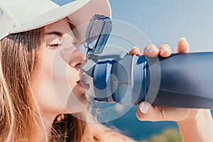 Fintess woman drinking water. Happy, active middle aged woman standing on beach and drinking water after excersise