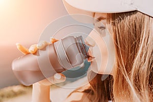 Fintess woman drinking water. Happy, active middle aged woman standing on beach and drinking water after excersise