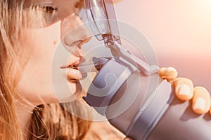 Fintess woman drinking water. Happy, active middle aged woman standing on beach and drinking water after excersise