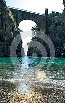 Fiordo di Furore, Amalfi coast, picturesque seascape view from beach on arched bridge between rocks and turquoise sea.