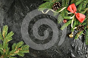 Fir branch with balls, gifts, pine cone and bows on a black wooden background