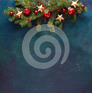 Fir branch with Christmas decoration on a dark blue-green painted wooden background. Flat lay.  New Year background with place for