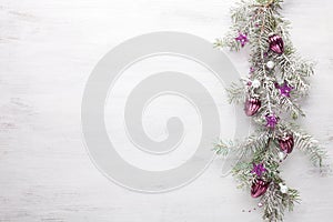 Fir branch with Christmas decoration on white shabby wooden board with copy space for text.