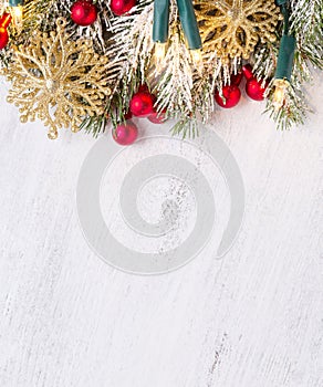 Fir branch with Christmas decorations and glowing garland on old wooden shabby background with empty space for text. Top view