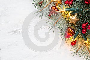 Fir branch with Christmas decorations and glowing garland on old wooden shabby background with empty space for text. Top view