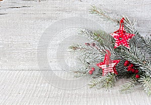 Fir branch with Christmas decorations on white rustic wooden background