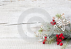 Fir branch with Christmas decorations on white rustic wooden background.