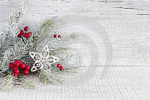 Fir branch with Christmas decorations on white rustic wooden background.