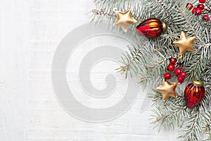 Fir branch with Christmas decorations on white rustic wooden background with copy space for text