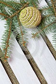 Fir branch and decorative balls on a background of wooden boards. The boards are painted white