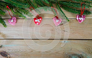 Fir branch with fabric hearts on the wood