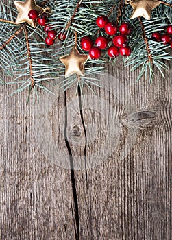 Fir branch with red berries and golden stars on an old wooden board with copy space for text. Christmas and New Year holidays back