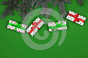 Fir branches and gift boxes on a green background. Background for Christmas and New Year cards. View from above. Copy space