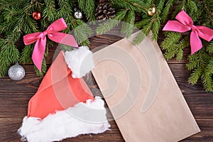 Fir branches, pink ribbon bow, Christmas cap, envelope and christmas balls. New Year background.