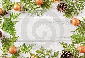 Fir branches, thuja twigs, golden Christmas balls, fir cones on a wooden background, place for the inscription