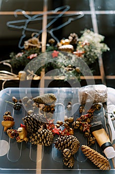 Fir cones, balls, threads and scissors for making a New Year wreath lie on the table