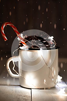 Fir cones in tin jar with sparkling star-shaped garland and single candy cane stick. Christmas decorations.