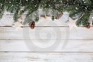 fir leaves and pine cones decorating rustic elements on white wood table with snowflake.