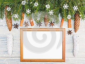 Fir tree branch with cones, cinnamon, anise, frame, snowflake on white wooden background