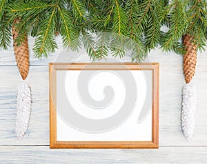 Fir tree branch with cones, frame, snowflake on white wooden background