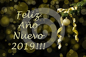 Fir tree branch with golden glitter ball and ribbon on dark background. Bokeh effects. New year greetings postcard Feliz AÃÂ±o photo