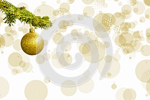 Fir tree branch with a golden glitter ball on white background. Bokeh effects. Christmastime. Christmas postcard