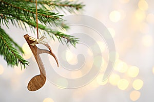 Fir tree branch with wooden note against blurred lights. Christmas music