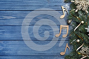 Fir tree branches with Christmas decor near decorative music notes and space for text on blue wooden background, flat lay