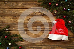 Fir tree branches with Christmas decoration and Santa cap against old vintage style wooden planks. Christmas/New Year concept.