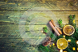 Fir tree branches cinnamon dried orange slices pine cones on old plank wood background. Golden bokeh lights. Christmas New Year