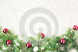 Fir tree branches decorated with red christmas balls as border on a rustic holiday background frame with snow copy space photo