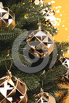 Fir tree with New Year decorations. Shiny gold colored Christmas ornaments.