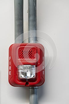 Fire alarm lighting in red plastic case installed against white