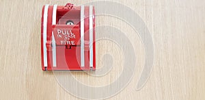 Fire alarm switch box for pull in case of fire isolated on light brown wooden background with right copy space.