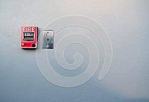 Fire alarm on white concrete wall. Warning and security system. Emergency equipment for safety alert. Red box of fire alarm