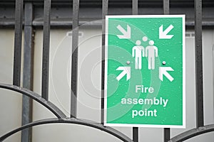 Fire assembly point sign at workplace car park fence