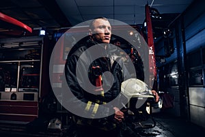 The fire brigade came to the call at night. Handsome fireman wearing a protective uniform with a flashlight included