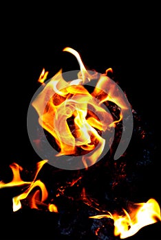 Fire burning on a black background. Texture of fire, flame on a dark background. Hot flame of red-yellow color.