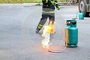 Fire burning on green gas container with Firefighter or fireman in black uniform and wheel background during fire safety training