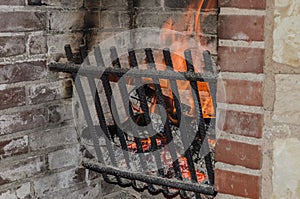Fire burns in a brick fireplace with a metal grate