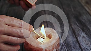 Fire candle scented, close-up of a woman's hand with a burning match lighting a candle for fire and lighting.