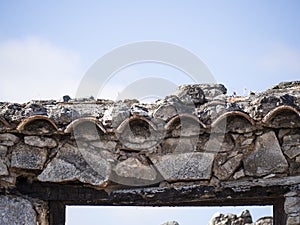 Fire damage on a terracotta tile roof. Burnt char and soot with a clear blue sky