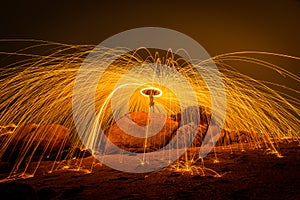 Fire dancer swing fire dancing show on the beach with dark clouds, twilight sky background.