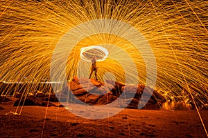 Fire dancer swing fire dancing show on the beach with dark clouds, twilight sky background.